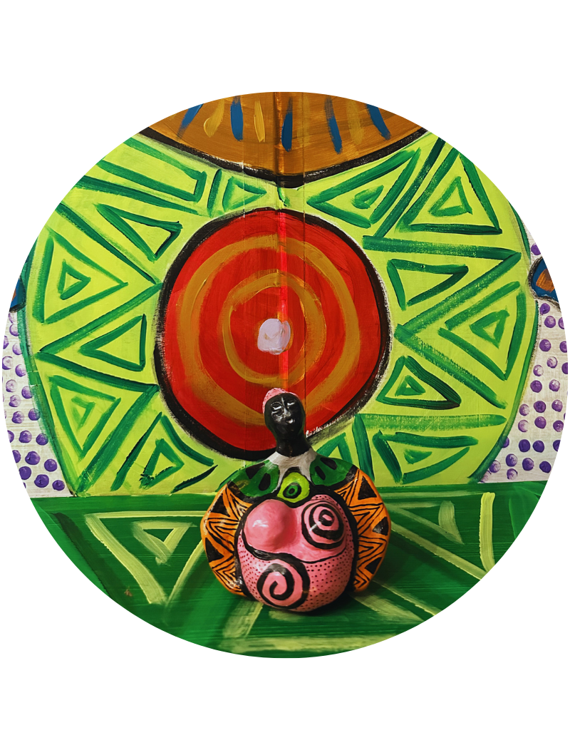 Photographie d'une statuette féminine peinte de motifs roses et noirs, placée devant un grand disque de bois peint avec des cercles concentriques rouges et orangés et des motifs triangulaires verts.