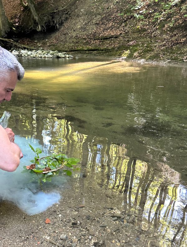Une personne accompagnée par Marguerite Lalèyê réalise un acte de psychomagie en nature — rituel symbolique en forêt pour traverser un seuil intérieur